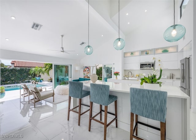 kitchen with sink, ceiling fan, plenty of natural light, white cabinets, and decorative light fixtures