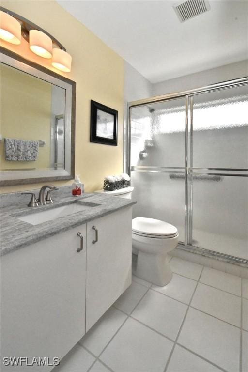 bathroom with toilet, vanity, tile patterned flooring, and a shower with door