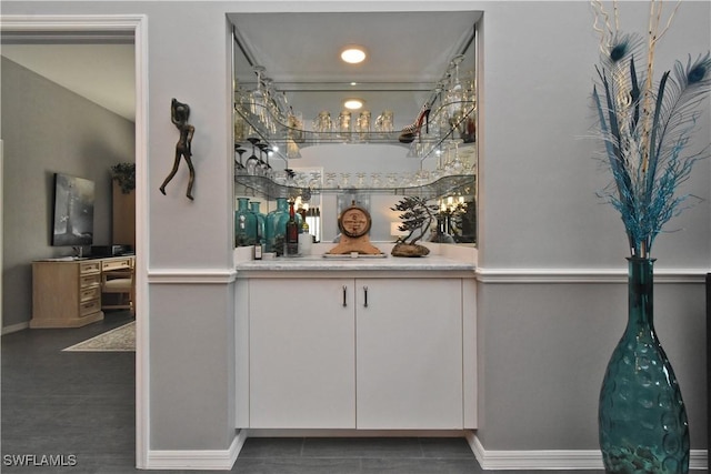 bar with dark tile patterned flooring and white cabinetry