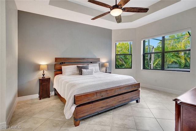 tiled bedroom with ceiling fan and a raised ceiling