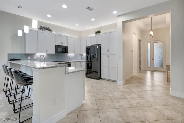 kitchen featuring white cabinets, black appliances, a kitchen bar, backsplash, and kitchen peninsula