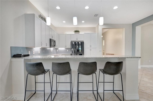 kitchen with white cabinetry, light stone counters, black appliances, decorative backsplash, and kitchen peninsula