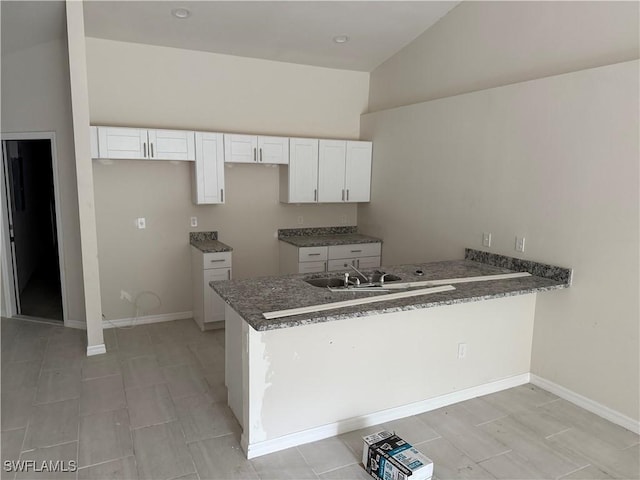 kitchen featuring white cabinetry, lofted ceiling, kitchen peninsula, and sink