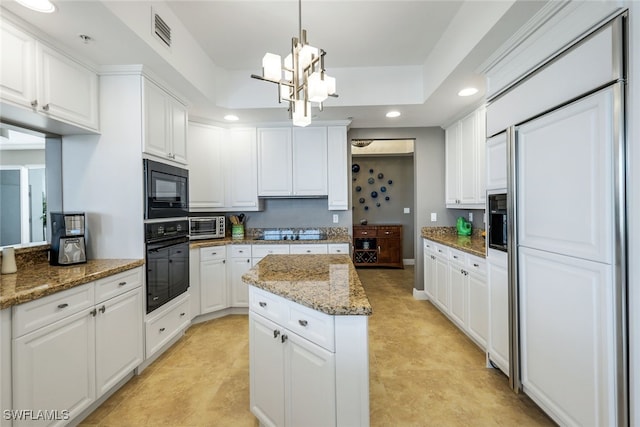 kitchen with black appliances, decorative light fixtures, stone counters, and white cabinetry