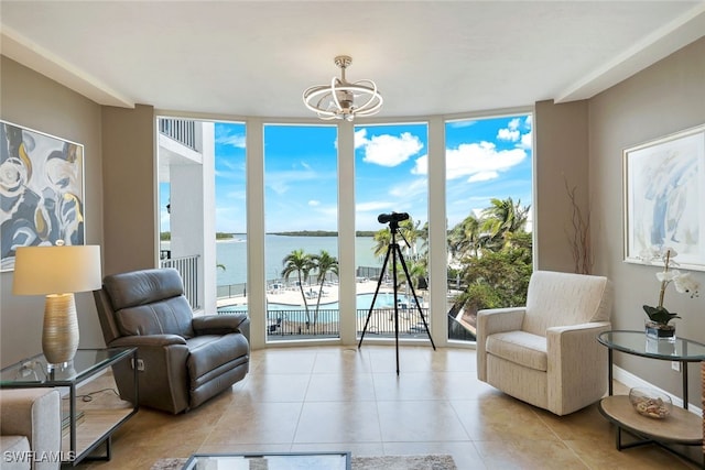 living area with light tile patterned flooring, a wall of windows, a water view, and an inviting chandelier