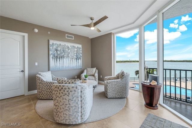 living room with a water view, light tile patterned floors, and ceiling fan