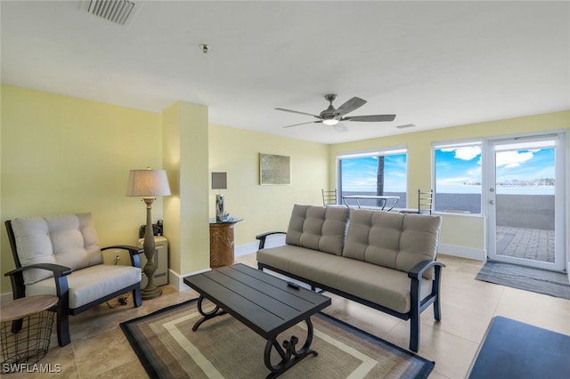 tiled living room with ceiling fan and a water view