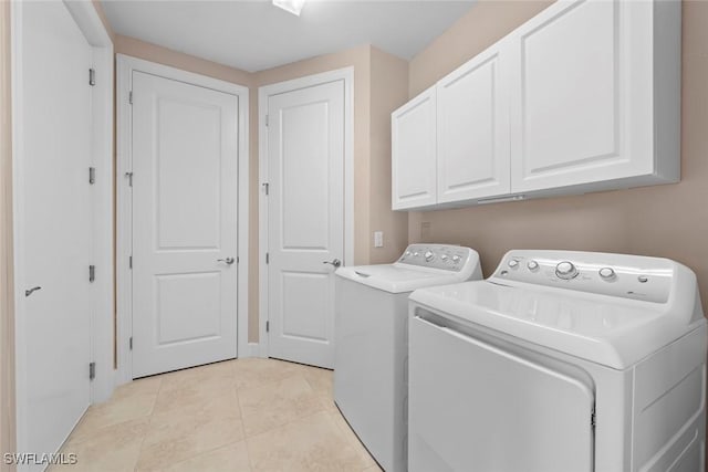 laundry room with light tile patterned floors, washing machine and dryer, and cabinets