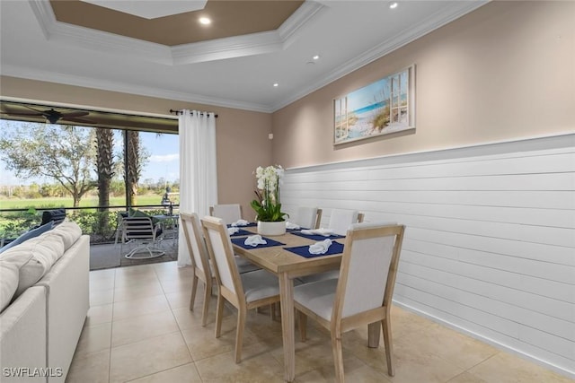 dining area with crown molding, a raised ceiling, light tile patterned flooring, and wood walls