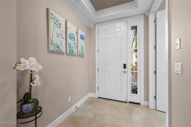 tiled foyer with ornamental molding and a tray ceiling