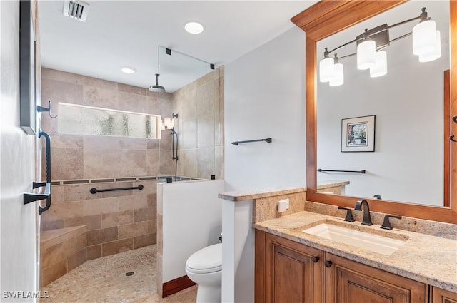 bathroom with toilet, vanity, and a tile shower