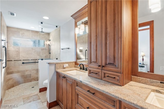 bathroom with tiled shower, vanity, and toilet