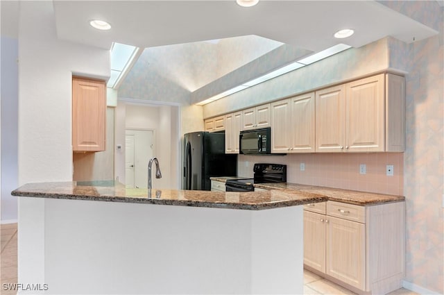 kitchen featuring dark stone countertops, black appliances, kitchen peninsula, and light tile patterned flooring