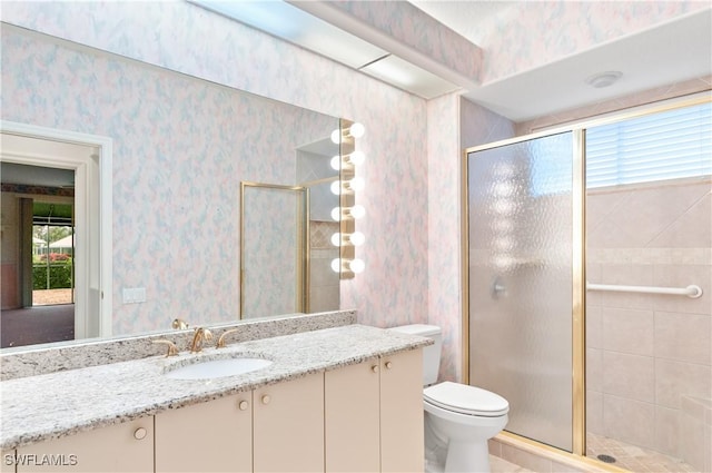 bathroom with vanity, a shower with door, and a healthy amount of sunlight