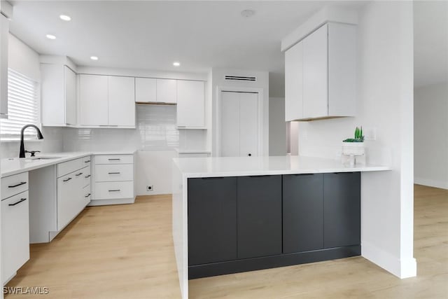 kitchen with sink, white cabinets, and light hardwood / wood-style flooring