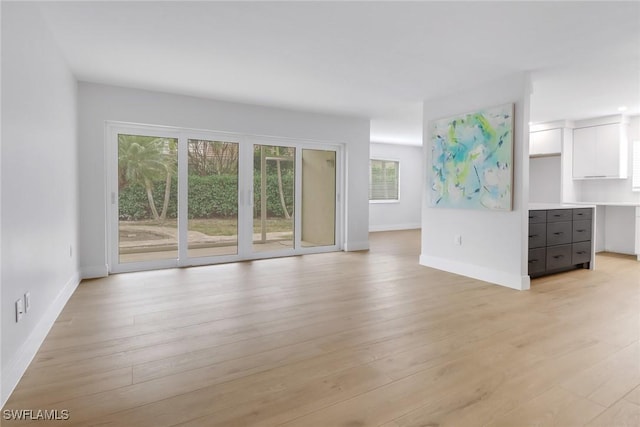 unfurnished living room with light wood-type flooring and baseboards