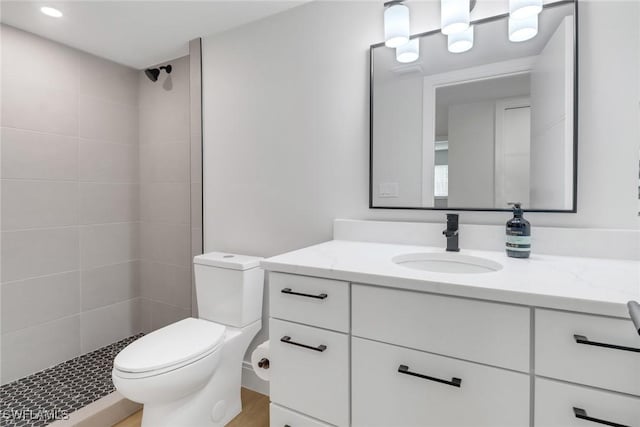 bathroom featuring toilet, vanity, and tiled shower