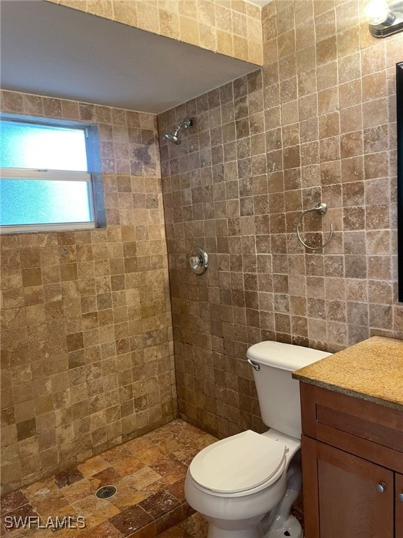 bathroom featuring toilet, vanity, and a tile shower