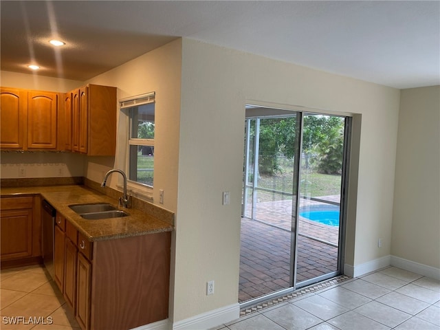 kitchen with light tile patterned floors, stainless steel dishwasher, and sink