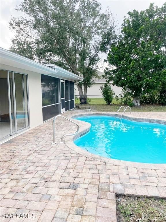 view of swimming pool featuring a patio area and a sunroom