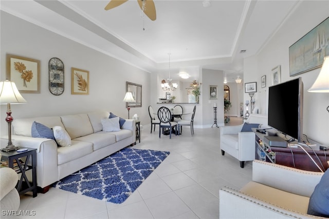 tiled living room with crown molding, a tray ceiling, and ceiling fan with notable chandelier