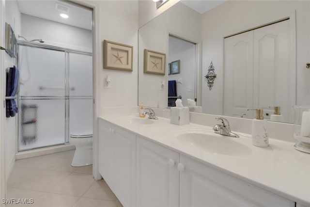 bathroom featuring tile patterned flooring, vanity, a shower with door, and toilet