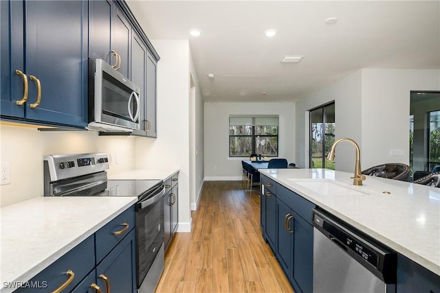 kitchen with light wood-type flooring, stainless steel appliances, blue cabinetry, and sink