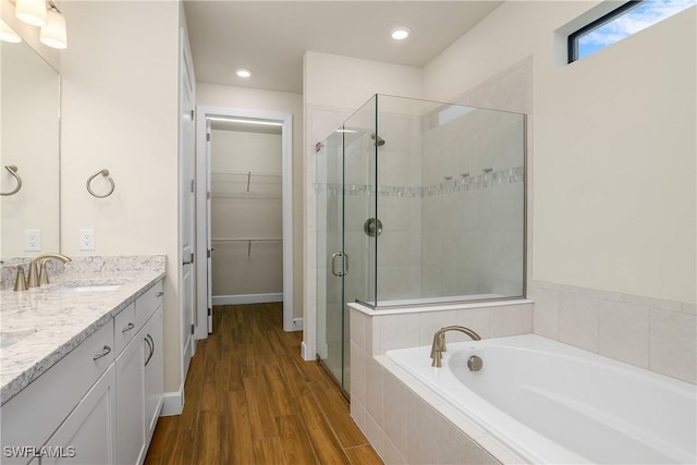 bathroom with hardwood / wood-style floors, vanity, and shower with separate bathtub