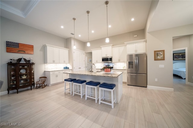 kitchen featuring white cabinetry, appliances with stainless steel finishes, tasteful backsplash, a kitchen island with sink, and sink