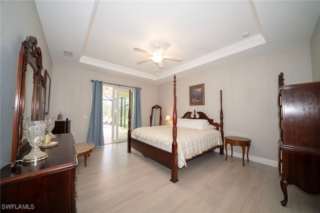 bedroom featuring ceiling fan, access to exterior, light hardwood / wood-style floors, and a tray ceiling