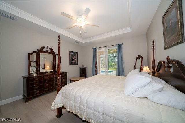 bedroom with access to outside, light wood-type flooring, ceiling fan, a tray ceiling, and crown molding