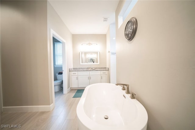 bathroom featuring toilet, a bathtub, hardwood / wood-style flooring, and vanity