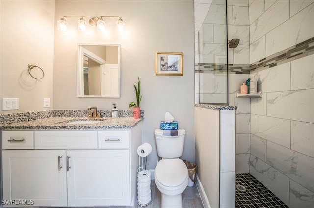 bathroom with tiled shower, vanity, and toilet