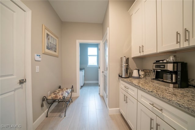 kitchen with light stone countertops, white cabinets, and light wood-type flooring