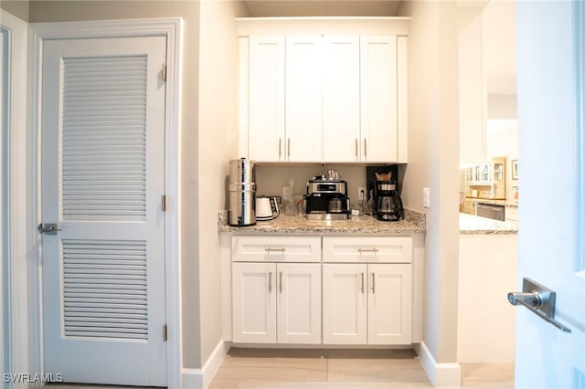 bar with dishwasher, white cabinets, and light stone counters