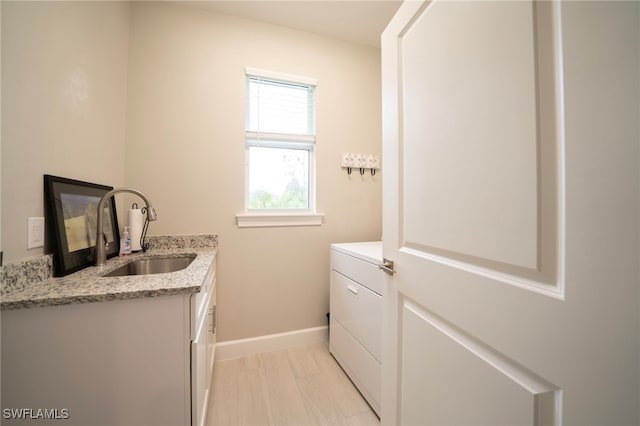 laundry room featuring washer / clothes dryer, light wood-type flooring, sink, and cabinets