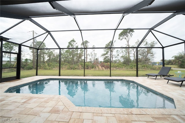 view of pool featuring glass enclosure, a patio area, and a lawn