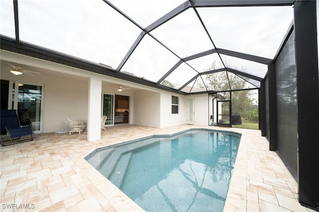 view of swimming pool with ceiling fan, glass enclosure, and a patio