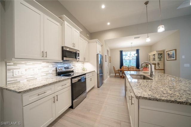 5435 Montego Ln, Port Charlotte, FL 33981 - kitchen with stainless steel appliances, a sink, decorative backsplash, white cabinets, and a center island with sink
