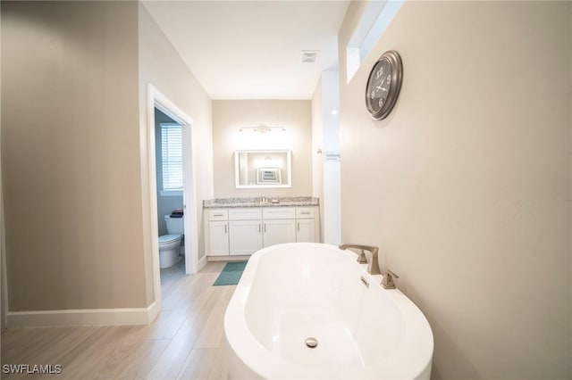 5435 Montego Ln, Port Charlotte, FL 33981 - full bath featuring wood finished floors, toilet, a freestanding tub, baseboards, and vanity