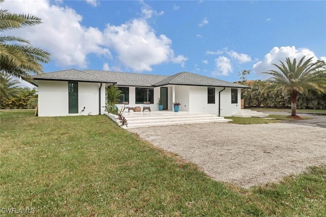 rear view of property with a lawn and stucco siding