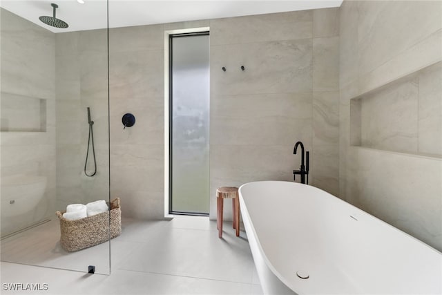 bathroom with tile patterned floors, a freestanding bath, tile walls, and tiled shower