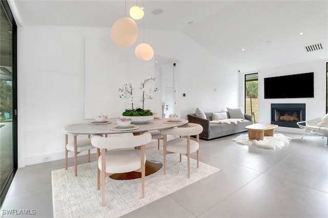 dining space with a fireplace, visible vents, and vaulted ceiling