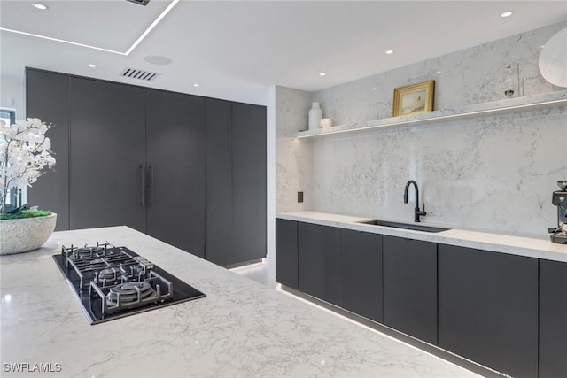 kitchen with black gas cooktop, visible vents, a sink, and dark cabinetry