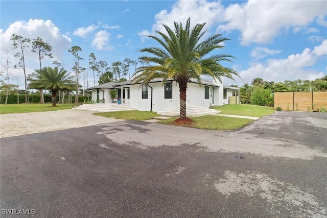 view of front facade with driveway, fence, and a front yard