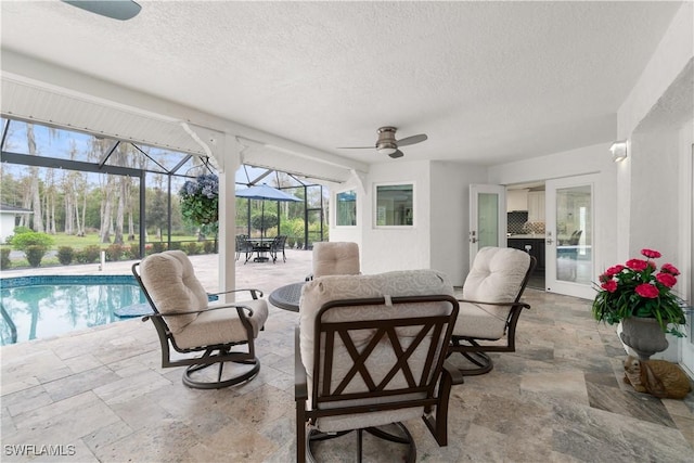 view of patio / terrace featuring ceiling fan and glass enclosure