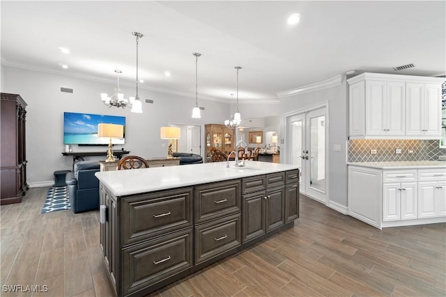 kitchen featuring pendant lighting, white cabinets, ornamental molding, and dark brown cabinets