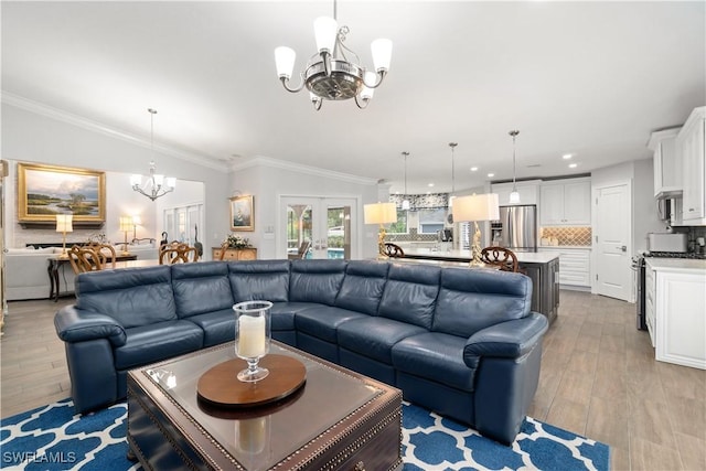 living room featuring vaulted ceiling, a notable chandelier, light hardwood / wood-style flooring, ornamental molding, and french doors