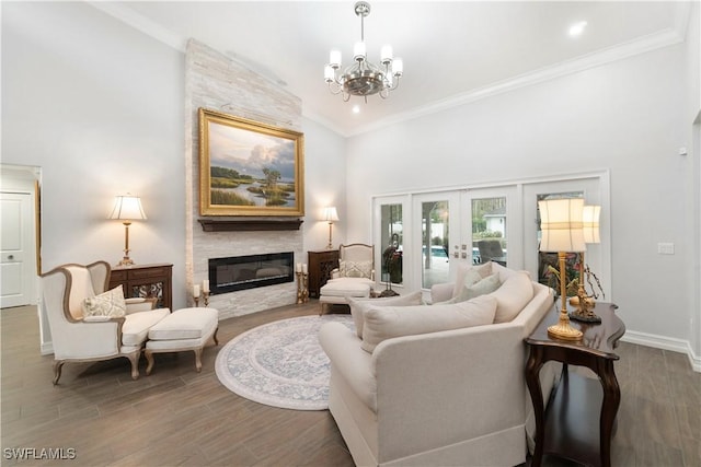 living room featuring lofted ceiling, french doors, a large fireplace, a notable chandelier, and crown molding