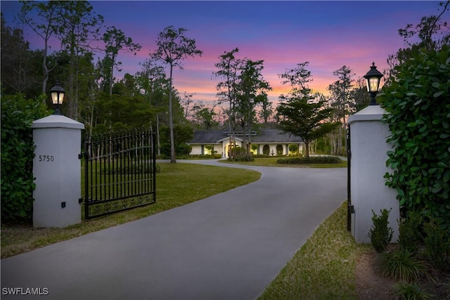 gate at dusk featuring a yard